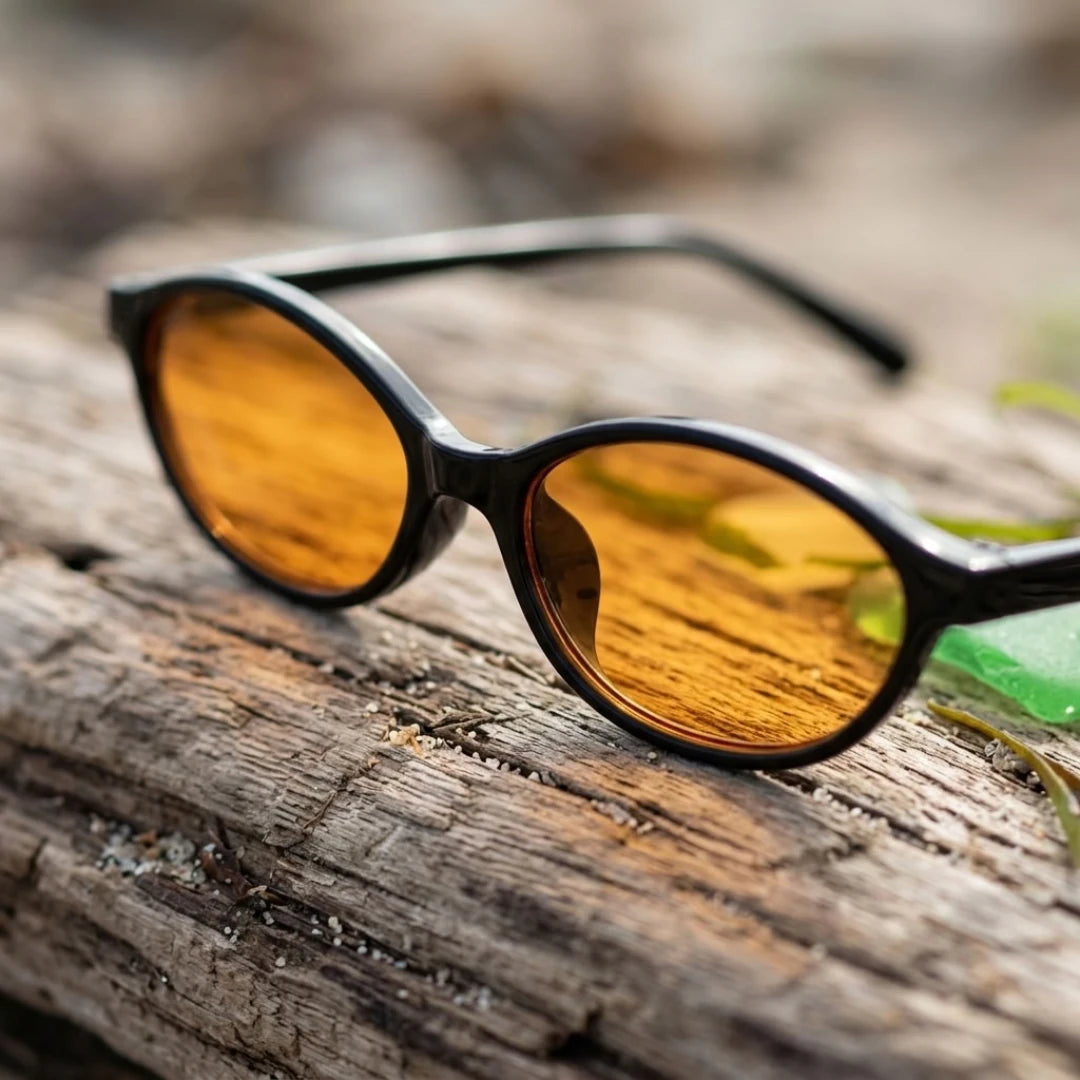 Detalhe da armação preta e das lentes amarelas do Mionelle Narrow Vibe Pop Yellow sobre madeira