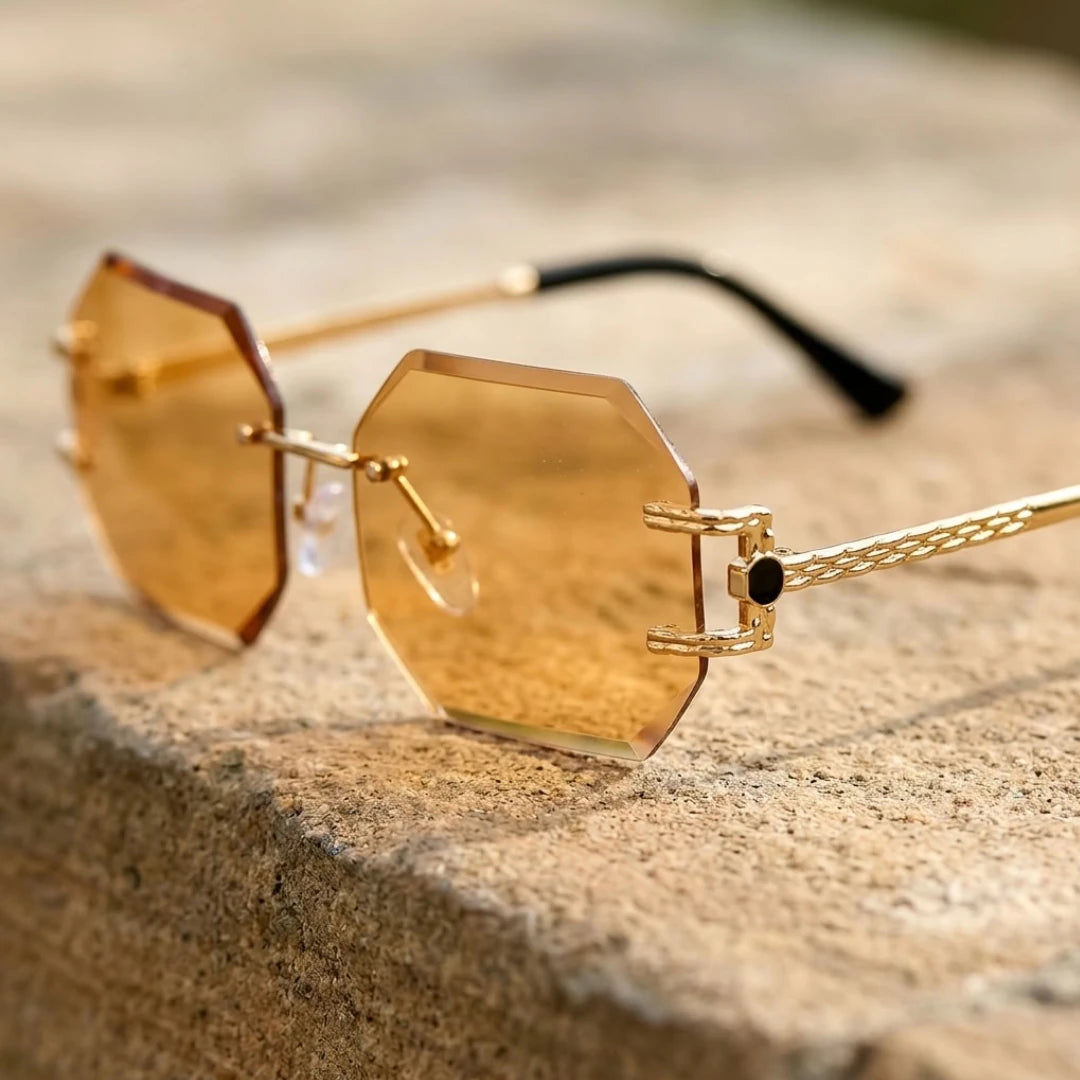 Detalhe dos óculos Mionelle Facet Champagne Gold sobre pedra, com lentes champagne e hastes douradas