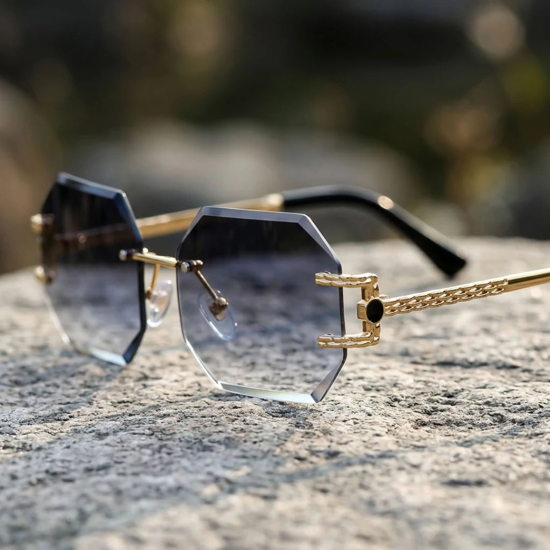 Detalhe dos óculos Mionelle Facet Shadow Black sobre pedra, com lentes cinza em degradê e ponte dourada