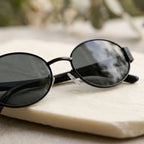 Detalhe das lentes dos óculos Mionelle Selene All Black sobre uma superfície clara