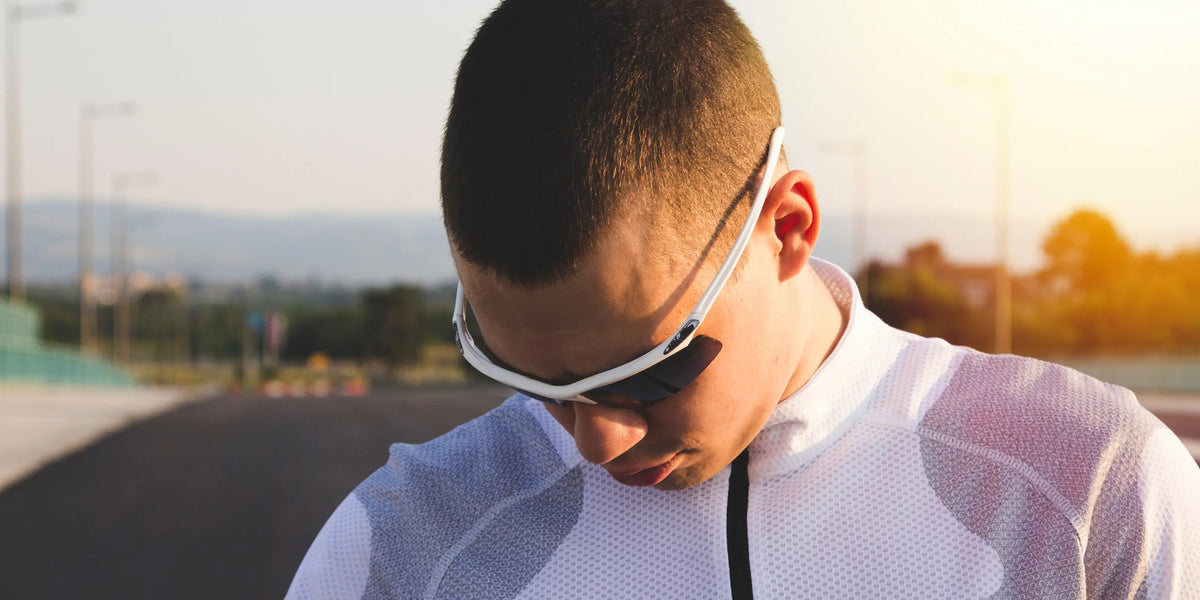 Homem usando óculos de sol esportivos brancos ao ar livre, em luz de fim de tarde